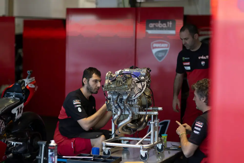 Mechaniker des Ducati Aruba.it Racing Teams bei der Wartung eines Hochleistungs-Rennmotors in der Boxengasse, repräsentativ für den Einsatz von Allengra Durchflussmesstechnik und präzisem Motormanagement im professionellen Motorsport.