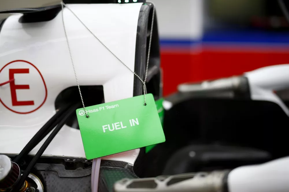 Primo piano della monoposto Haas F1 Team con cartellino verde “FUEL IN” appeso vicino all’ingresso carburante nel box